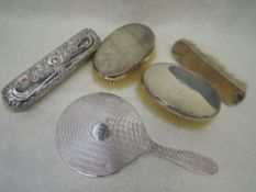 Five HM silver dressing table items including four brushes and a mirror
