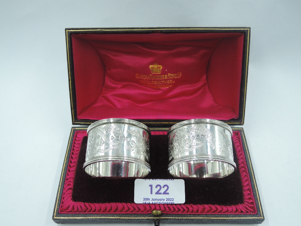 A cased pair of Edwardian silver napkin rings having brightcut decoration and monogrammed