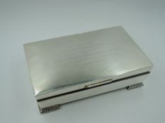A silver cigarette box of plain casket form having bracket feet and presentation inscription