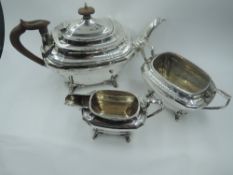 A silver three piece tea service of tapered and canted oval form having soft wood handles and