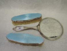 A silver dressing table hand mirror and two brushes, all having turquoise guilloche enamelled