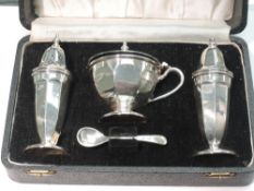 A cased silver three piece cruet set of facetted urn form, having blue glass liner, Sheffield 1949/