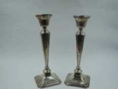 A pair of silver candlesticks of dainty form having plain tapered square columns and weighted square