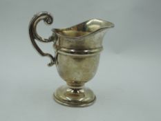 A small silver cream jug of helmet form having raised moulded loop handle and pedestal foot, Chester