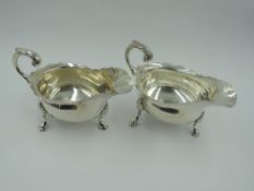 A pair of Edwardian silver sauce boats of traditional form having trefoil hoof feet, loop handles