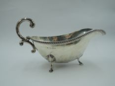 A silver sauce boat having trefoil hoof feet, loop handle & gadrooned rim, Birmingham 1929,