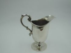 A silver cream jug of plain helmet form having moulded loop handle and circular pedestal foot,