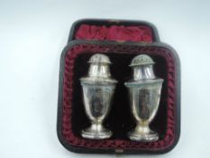 A cased pair of Victorian silver pepperettes of urn form having push on lids, Sheffield 1887/90,