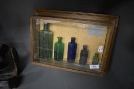 A selection of framed and cased antique poison bottles