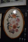 A framed needle work embroidery of a floral scene framed and glazed