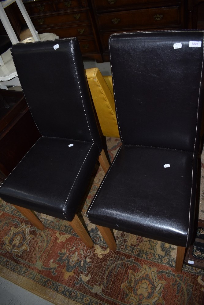 A pair of modern dark brown leather effect dining chairs on wood legs