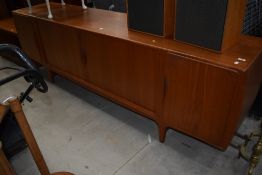 A mid century teak long side board having rolling doors and compartmental inside in good condition