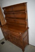 An Ercol mid elm dresser having shaped Delft rack over drwers and cupboards, w123cm