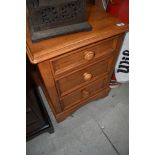 A modern stained rubber wood bedside chest of 3 drawers