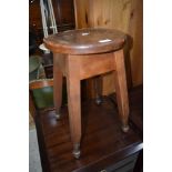 An early 20th century elm stool having circular top on splay legs