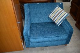 A modern teal covered day chair with fold out bed under