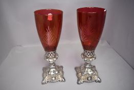 A pair of candle sticks having cranberry glass shades by Oneida
