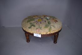 A wood framed late 19th/early 20th century needlepoint foot stool.