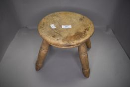 A beech wood low stool having turned legs