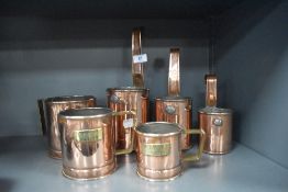 A set of graduated copper measuring cups with brass name plates including Dale Farm