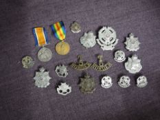 A collection of Border Regiment Cap Badges, Helmet Badge, Badges and Brooches and a pair of WW1