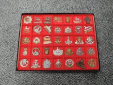A display tray of Thirty Five metal Military Cap Badges including South Wales Borderers, Kings