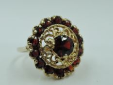 A garnet dress ring having a central garnet with wire work decoration within a further ring of