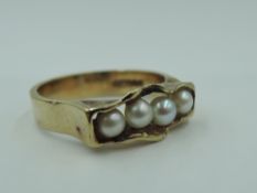 A 9ct gold ring having four seed pearls in a naturalistic style channel mount on a 9ct gold loop,