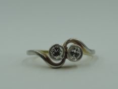 A two stone diamond ring, total approx 0.15ct in collared mounts to crossover shoulders on a