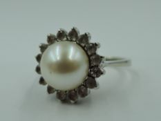 A cultured pearl and white stone cluster dress ring in claw set basket mount on a white metal loop
