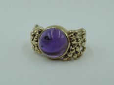 A 9ct Artisan style ring having a purple cabouchon stone in a collared mount to naturalistic