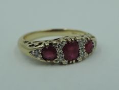A ruby dress ring having a trio of rubies interspersed by diamond chips in a gallery mount on a