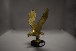 A brass cast figure of an eagle in flight on marble base