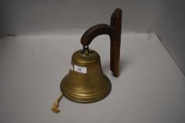 A pub or tavern style cast brass bell with oak bracket