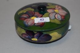 A Moorcroft pottery lidded bowl, tube-lined in the clematis pattern against a washed green ground,