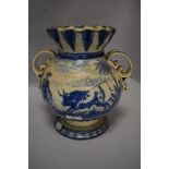 A 19th/20th century tin glazed twin handled vase having blue and white pattern and fluted neck.