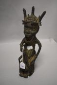 A Benin bronze figure of a tribal eldar, seated with sword in hand 31cm tall