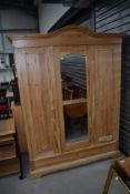 A rustic pine triple wardrobe having central mirror door, part fitted interior , slot construction