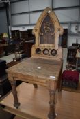 A Victorian Gothic golden oak hall chair, monogram to rear panel, ES