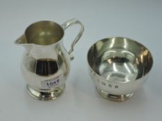 A silver cream jug and sugar bowl of plain form bearing oversized hallmarks, London 1974, Payne &