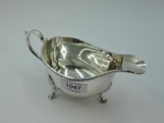 A silver sauce boat of traditional form having loop handle and trefoil hoof feet, London 1957, S J