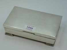 A silver cigarette box of plain casket form having bracket feet and presentation inscription