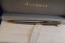 A boxed Waterman ballpoint pen in brushed steel with gold trim, made in France