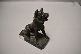 A small carved serpentine figure of a seated dog, with alert expression, on a canted rectangular