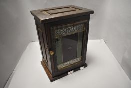 A small stained wood comunion cup cupboard, the hinged door with coloured and leaded glass panel