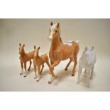 A matt white Beswick foal,a brown gloss Beswick horse and two Royal Doulton brown gloss foals.