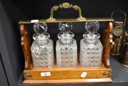 An early 20th century oak Betjemanns patent Tantalus having three cut glass bottles, devoid of key.