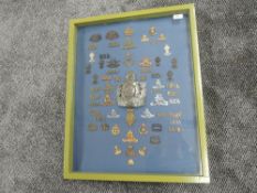 A framed and glazed display case containing Military Shoulder Titles, Cap Badges & Helmet Plates for