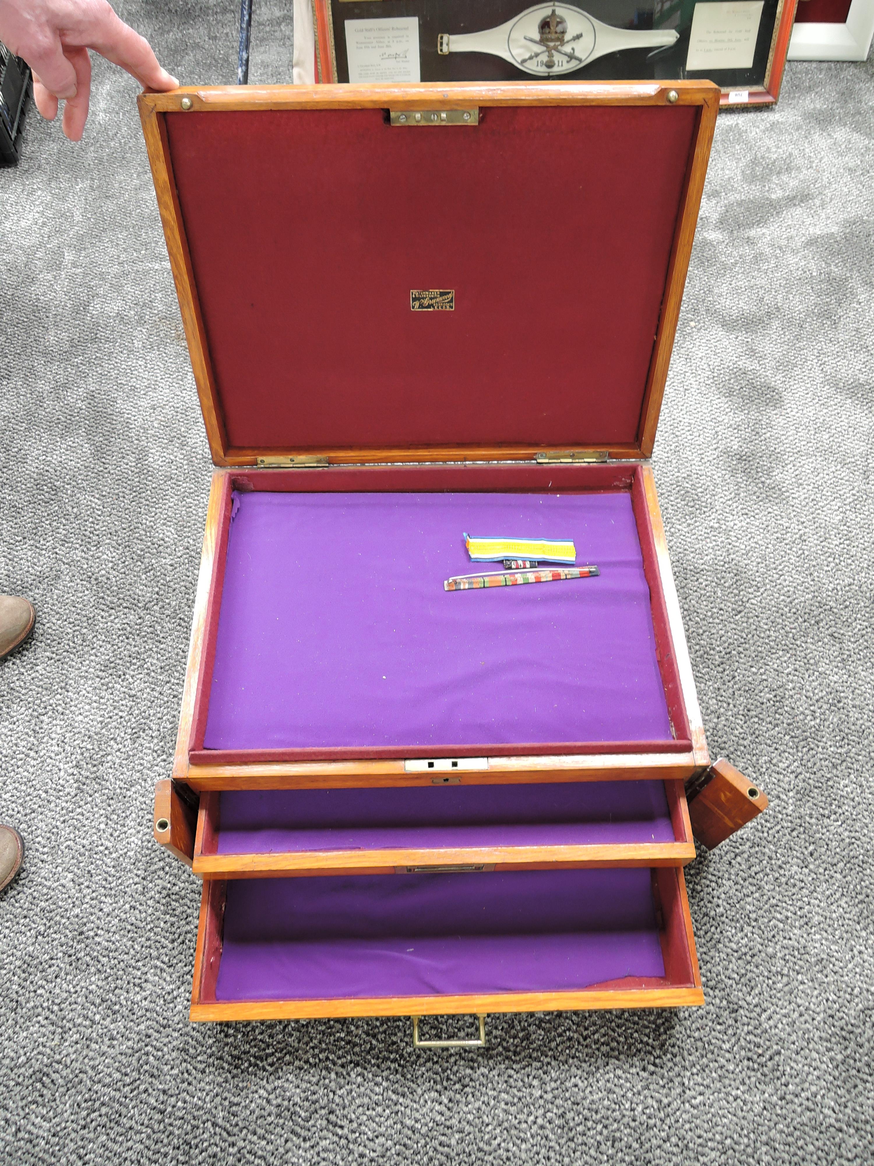 A wooden two drawer collectors cabinet having lift top display retailed by W Greedwood Leeds