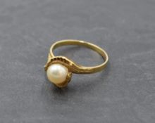 A cultured pearl solitaire dress ring in a stylised cross over wave raised mount to yellow metal